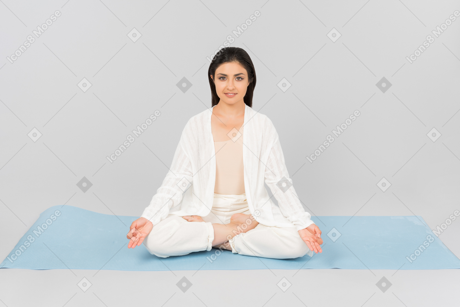 Donna indiana che si siede con le gambe incrociate sul tappetino yoga