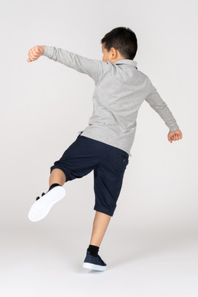 Rear view of a boy kicking something