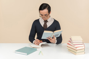 Junger asiatischer student in einer strickjacke ein buch lesend