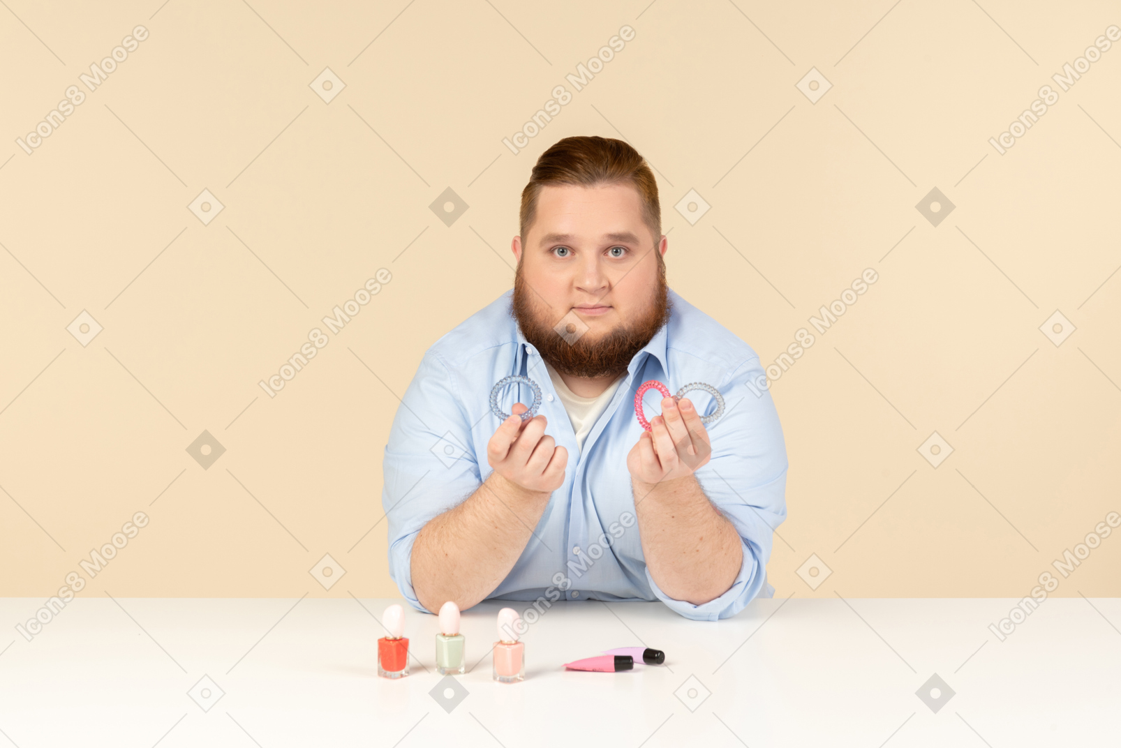 Большой человек сидит за столом и держит ленты для волос