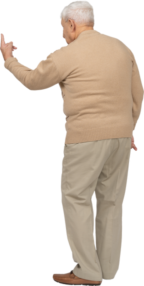 Vista trasera de un anciano con ropa informal que muestra el signo v