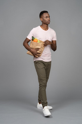 Un jeune homme portant un sac d'épicerie