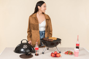 Young asian woman standing near grill and throwing a fruit