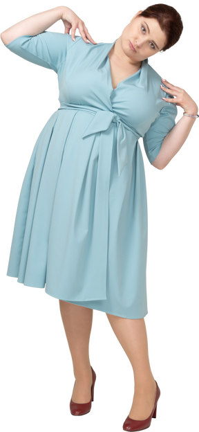 一个身着蓝色连衣裙的女人双手放在肩上站立的前视图