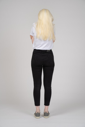 Back view of a young blonde girl standing and feeling cold
