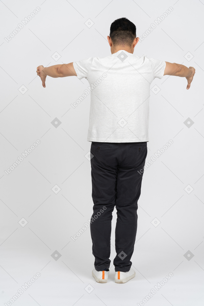 Vista posteriore di un uomo in abiti casual che mostra i pollici verso il basso
