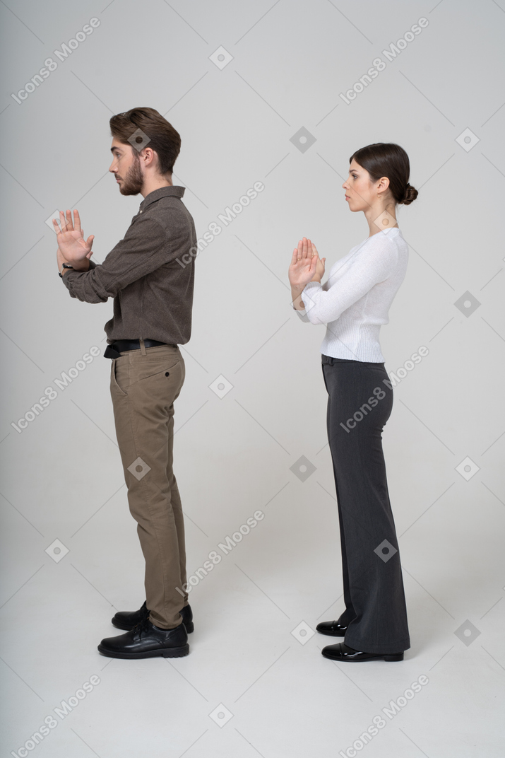 一对年轻夫妇在办公室服装交叉双臂的侧视图