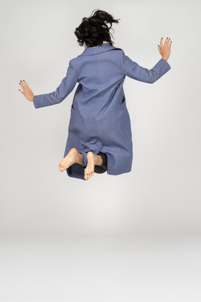 Back view of woman jumping with folded legs