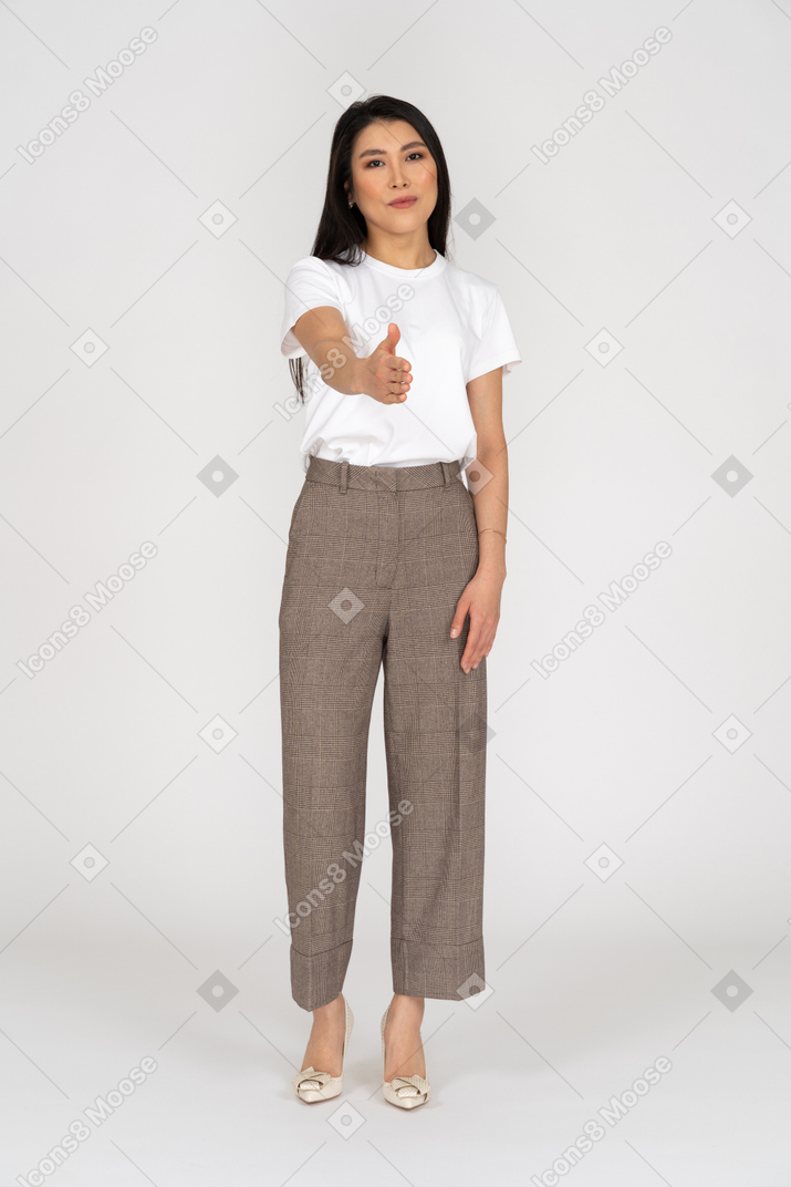 Front view of a greeting young lady in breeches and t-shirt outstretching her hand