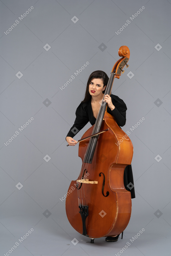 Vista di tre quarti di una giovane donna annoiata che suona il contrabbasso