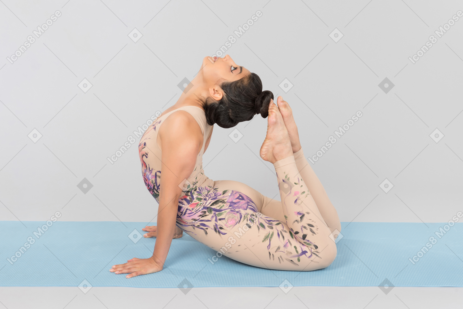 Flexible young indian woman lying on yoga mat and touching head with toes