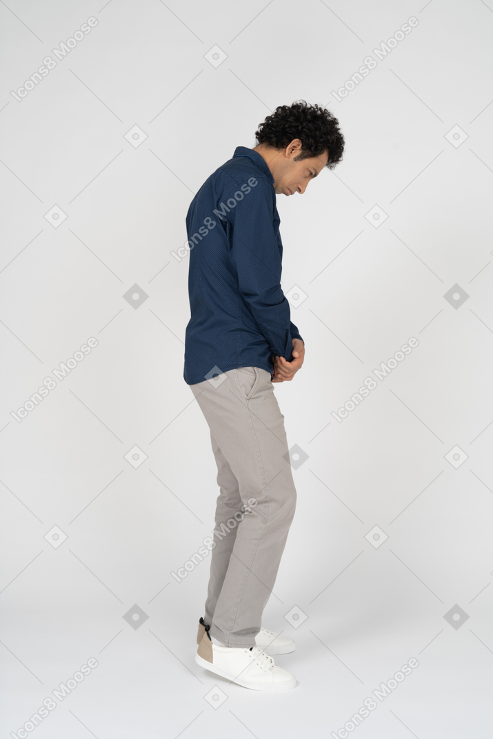 Vista lateral de um homem com roupas casuais olhando para baixo