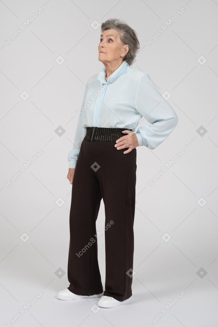 Three-quarter view of an old woman looking up expectantly with hand on her hip