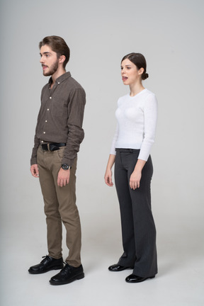 Трехчетвертный вид молодой пары в офисной одежде, показывающей язык