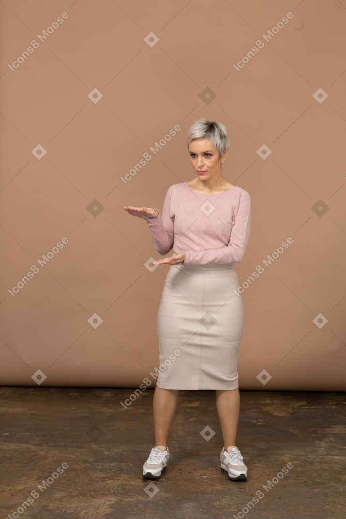 Vista frontal de una mujer impresionada en ropa casual que muestra el tamaño de algo