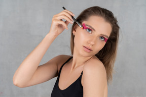 Portrait of a young woman putting eyeshadow on