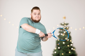 Der dicke kerl freut sich, zu weihnachten einen tennisschläger zu bekommen