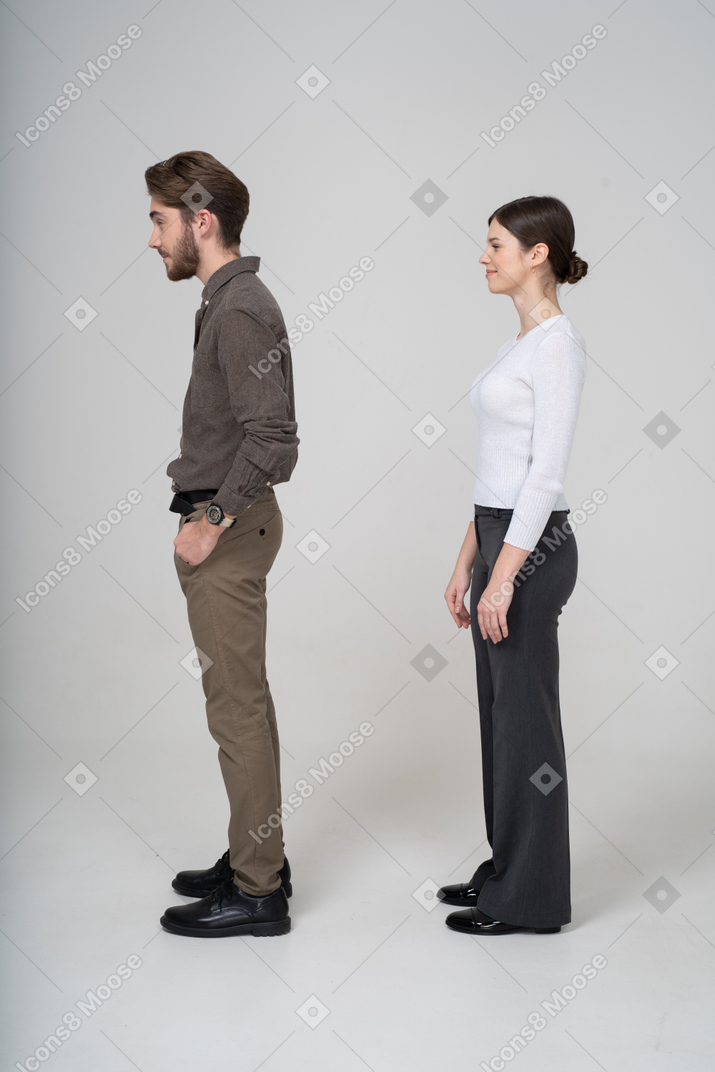 Подозрительная молодая пара в офисной одежде, вид сбоку