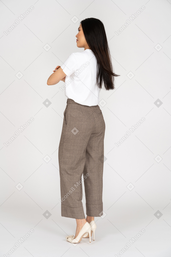 Vista posteriore di tre quarti di una giovane donna in calzoni che incrociano le mani