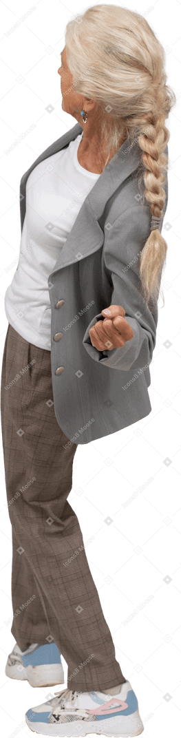 Вид сзади на старушку в костюме, наклонившуюся и показывающую кулак