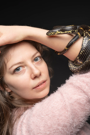 Striped black snake curving around woman's hand