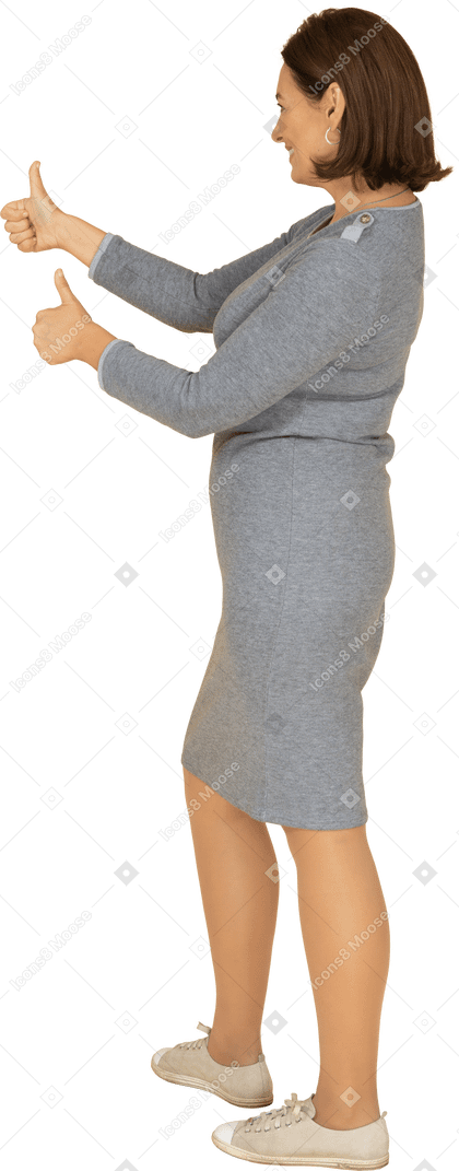 Вид сбоку женщины в сером платье показывает палец вверх