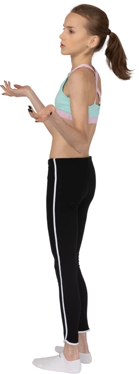 Three-quarter back view of a careless teen girl in sportswear raising hands