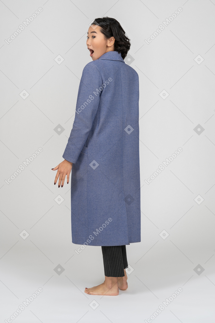 Mulher surpreendida com casaco olhando por cima do ombro