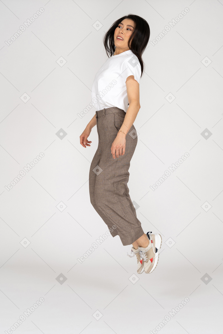 Dreiviertelansicht einer springenden jungen dame in reithose und t-shirt