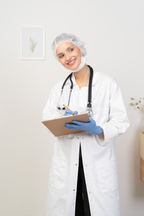 Vista frontal de uma jovem médica fazendo anotações em seu tablet