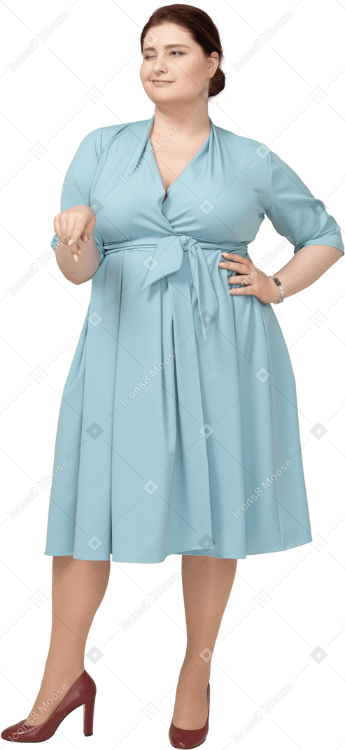 Front view of a woman in blue dress pointing down with a finger