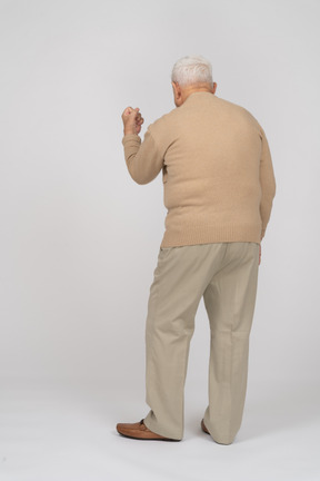 Retrovisione di un uomo anziano in abiti casual che mostra il pugno