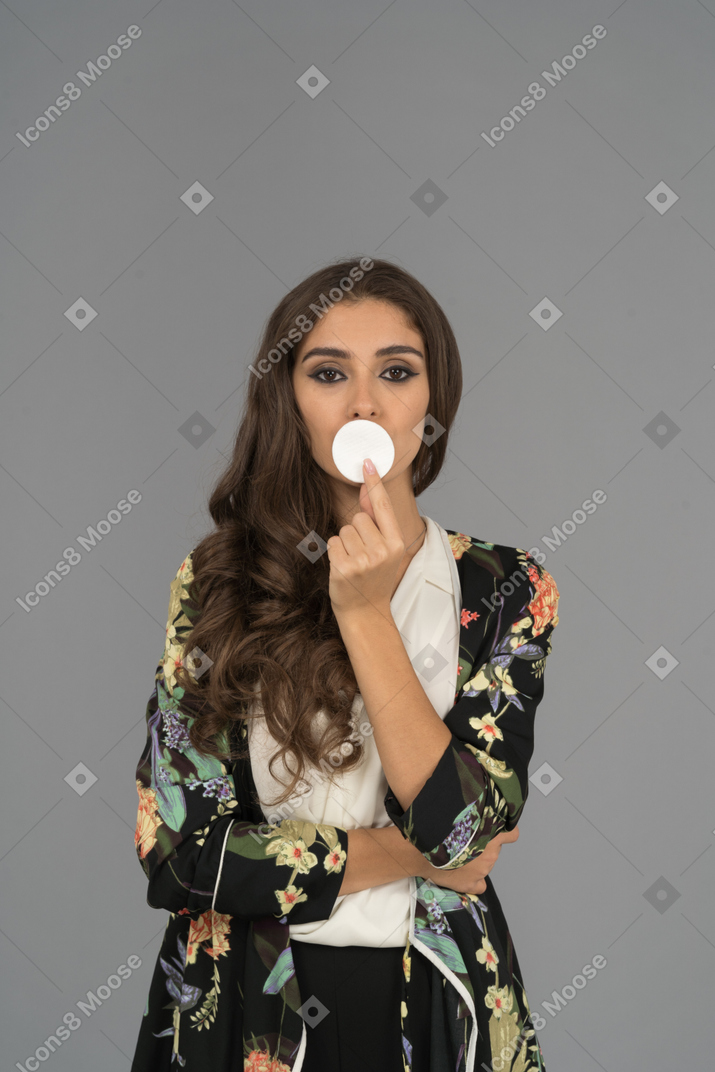 Mulher jovem e bonita cobrindo a boca com uma almofada de algodão