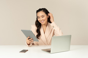 Empleado de oficina asiático arreglando el cabello y mirando en tableta