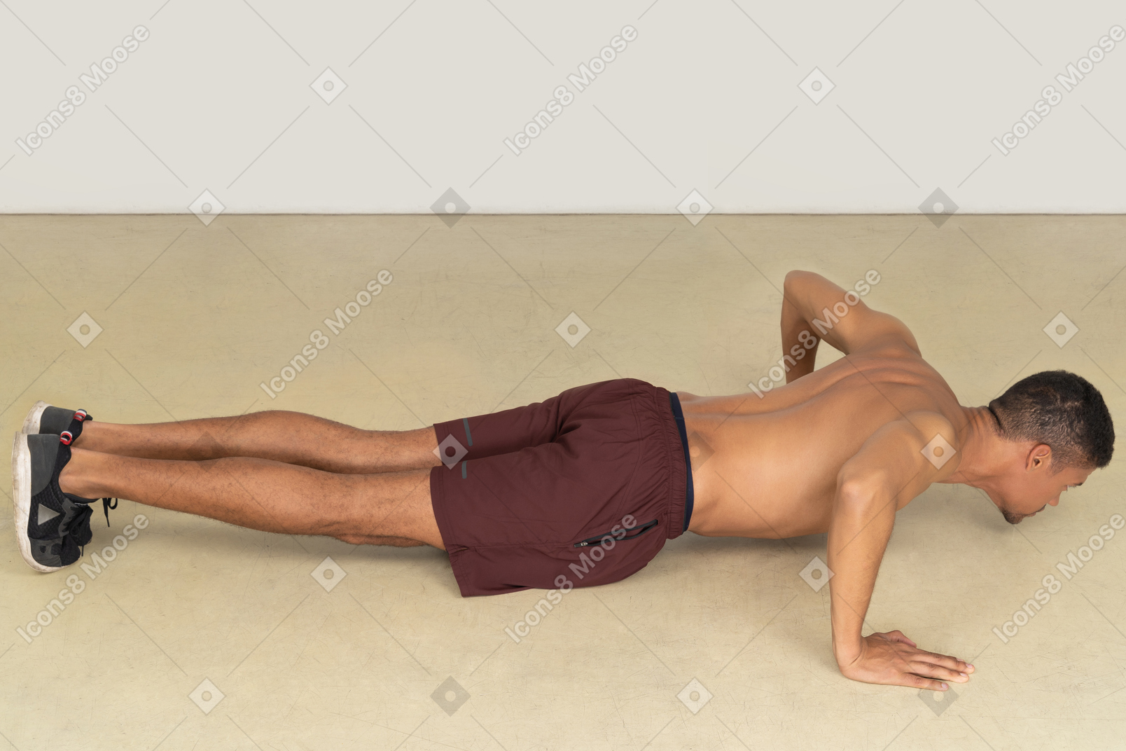A side view of the beautiful tall guy doing some exercises on the floor