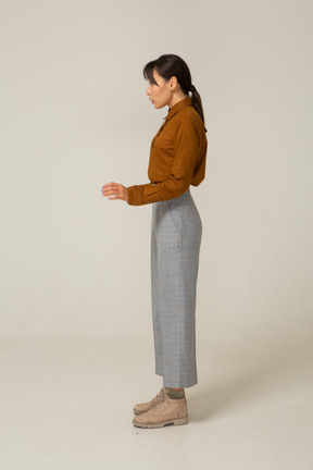 Side view of a young asian female in breeches and blouse raising her hands