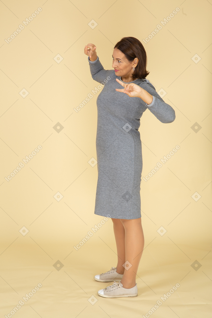 身振りで示す灰色のドレスを着た女性の側面図