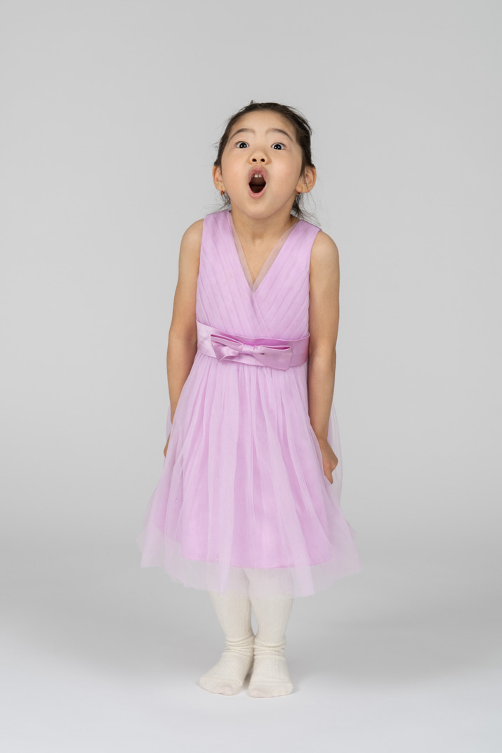 Little girl in pink dress standing amazed