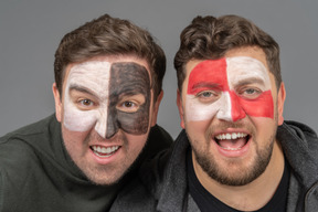 Front view of two male football fans with face art