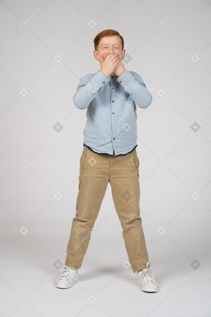 Front view of a cute boy covering mouth with hands