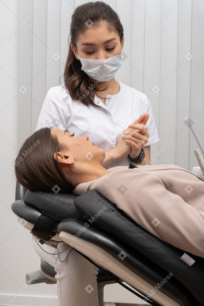 A female dentist talking to her female patient while putting hands together