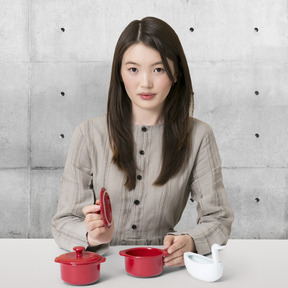 A woman sitting at a table with two red pots