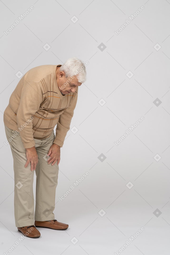 Old man in casual clothes bending down