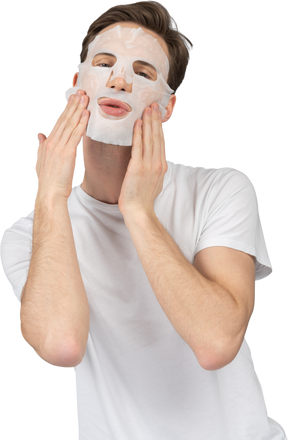 Vue de face d'un jeune homme posant dans un masque facial