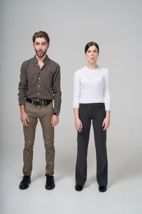 Front view of a young couple in office clothing tucking cheeks in