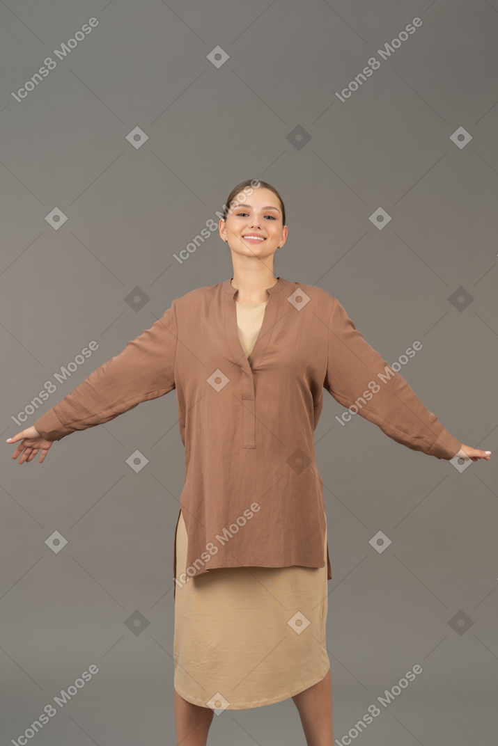 Giovane donna sorridente in piedi con le braccia e le gambe spalancate