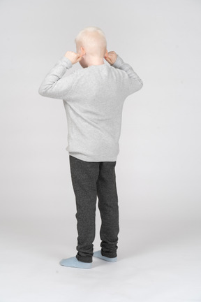 Back view of a little boy pulling his ears