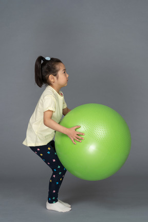 Niña sosteniendo un fitball verde