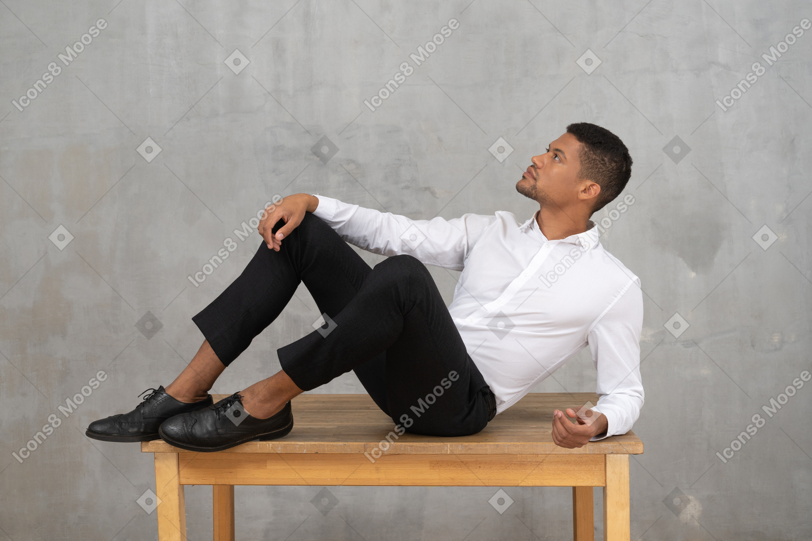 テーブルの上に横たわるフォーマルな服装の男