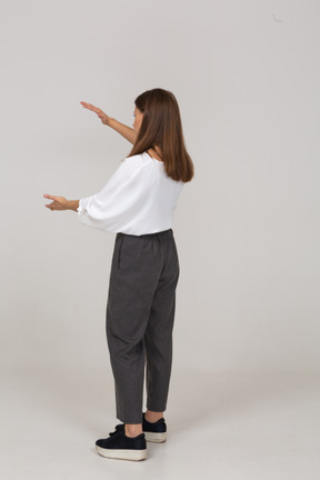 Vista traseira a três quartos de uma jovem com roupas de escritório, mostrando o tamanho de alguma coisa